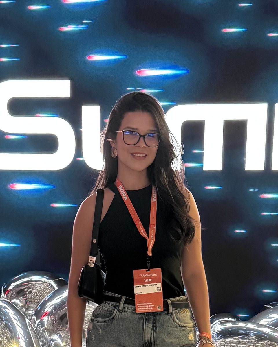 Nayara Medeiros sorrindo, de óculos e blusa preta, em um evento de marketing